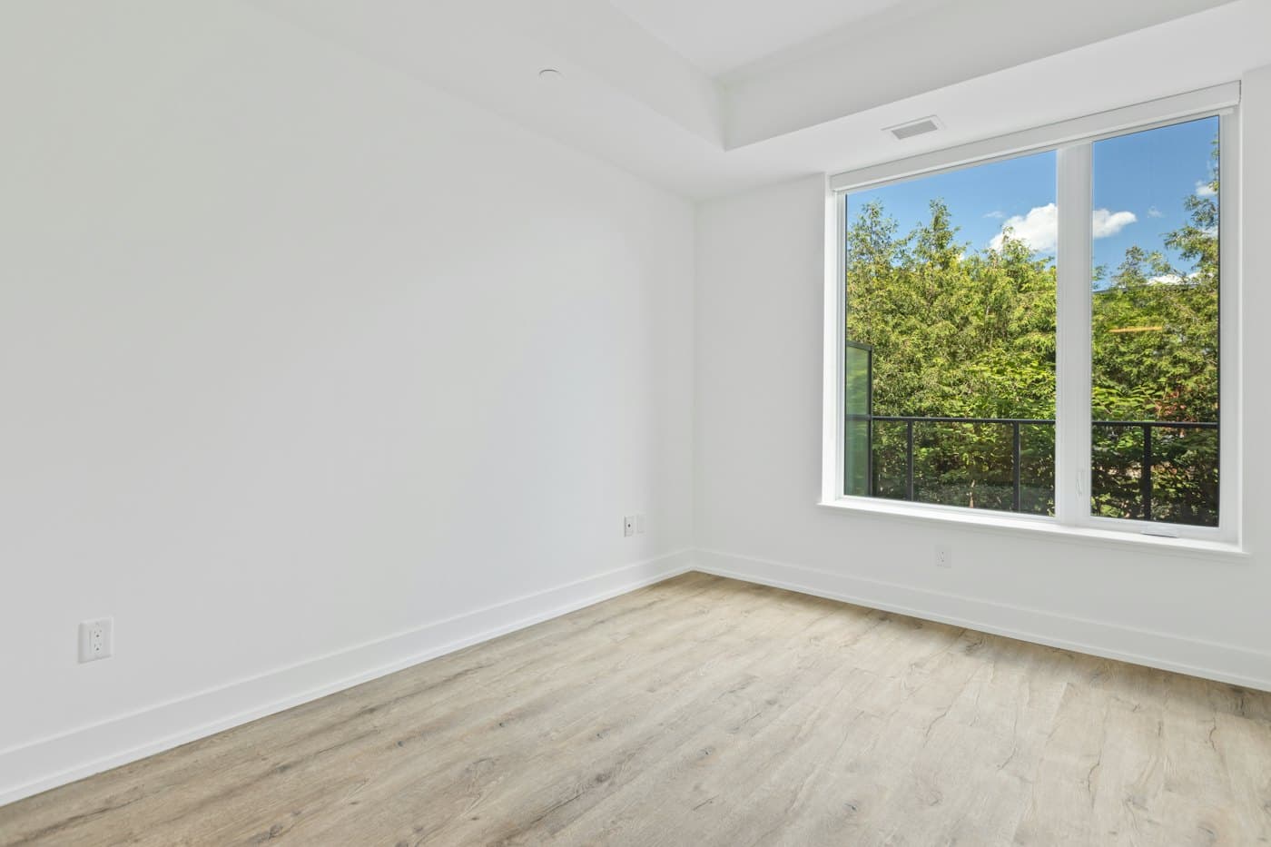 An empty, bright room with light floors and a window